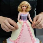 A baker carefully inserting a Barbie doll into the center of a cake, ensuring it is stable and well-positioned.